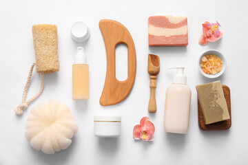 Composition with wooden guasha body massage tool and bath supplies on white background