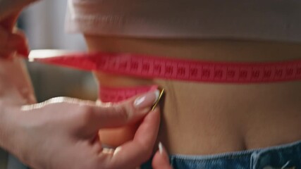 Closeup hands measuring waist stomach holding tape. Woman checking weight loss