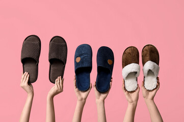 Female hands holding different male slippers on pink background