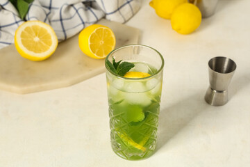 Glass of lemonade with lemons and mint on white background