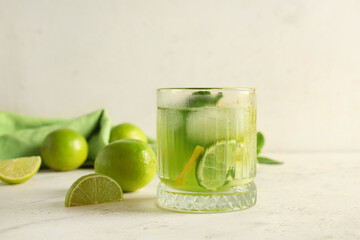 Glass of tasty lemonade with lime and mint on white background