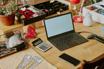 Home office desk featuring laptop, smartphone, and calculator alongside office supplies, plants, and decorations creating an organized and functional workspace