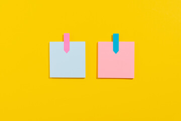 Empty blue and pink paper sheets for notes on yellow background. Office and school supplies on yellow background. Back to school concept