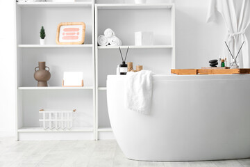 Aroma diffusers, towel and wooden tray on bathtub in bathroom