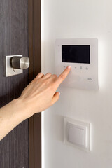 Woman hand pressing button on intercom system, opening front door