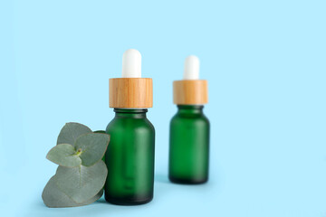 Bottles of eucalyptus essential oil on blue background, closeup