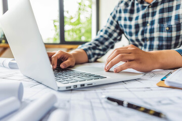 Architecture engineer working with blueprints and laptop in office. Inspection in workplace for architectural plan
