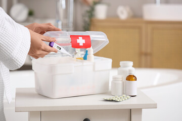 Woman taking thermometer from home first aid kit in bathroom, closeup