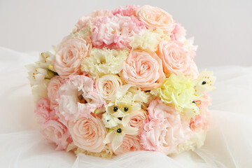 Beautiful wedding bouquet and bride's veil on light background