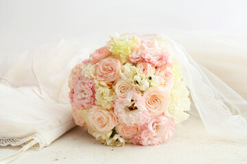 Beautiful wedding bouquet and bride's dress on light background