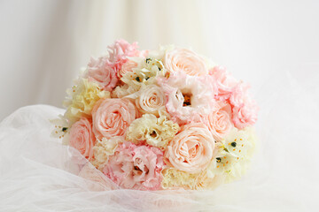 Beautiful wedding bouquet and bride's veil on light background