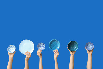 Hands holding empty plates on blue background