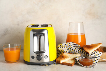 Yellow toaster with bread slices and glass of juice on white background