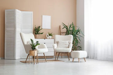 Folding screen, armchairs and different houseplants near beige room in living room