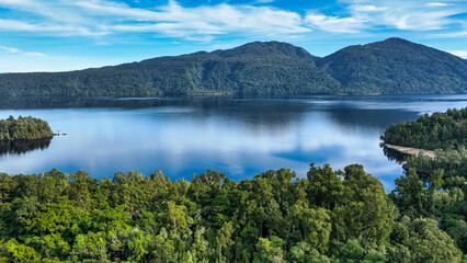 Fototapeta premium Drone view of an alpine lake surrounded by trees and forest