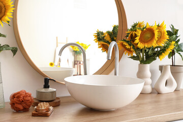 Sink, mirror and sunflowers in bathroom. Closeup