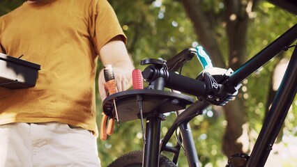 Up-close perspective of male caucasian hand selecting and preparing professional equipment for servicing bicycle. Sports-loving man arranging specialized tools for bike repair and maintenance.