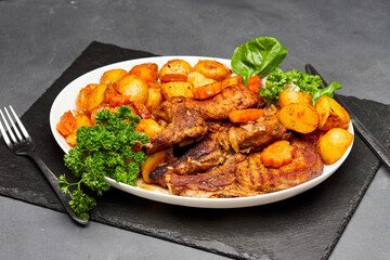 Roasted lamb with golden potatoes and carrots, garnished with fresh herbs for a hearty meal
