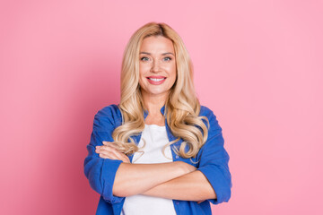 Portrait of confident lovely positive woman with wavy hairstyle dressed blue shirt holding arms crossed isolated on pink color background