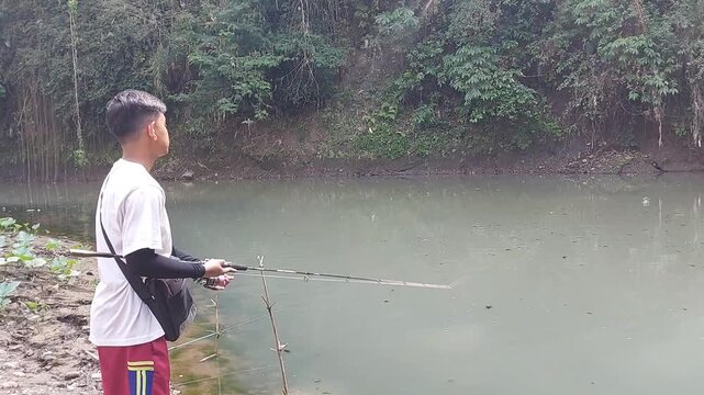 a man who was doing his fishing hobby using casting techniques in a river in the Magelang area, Central Java, Indonesia
