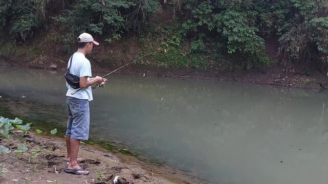 a man who is fishing using a casting technique in a river in the Magelang area, Central Java, Indonesia
