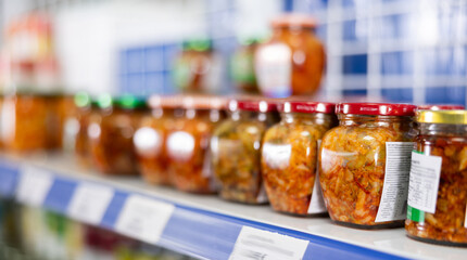 Jars of mustard stand in row on shelf in asian goods store