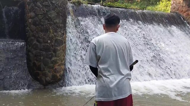 a man who was doing his fishing hobby using casting techniques in a river in the Magelang area, Central Java, Indonesia