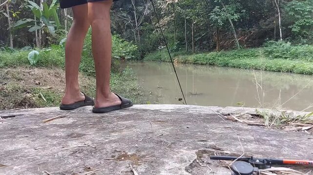 a man who is fishing using a casting technique in a river in the Magelang area, Central Java, Indonesia
