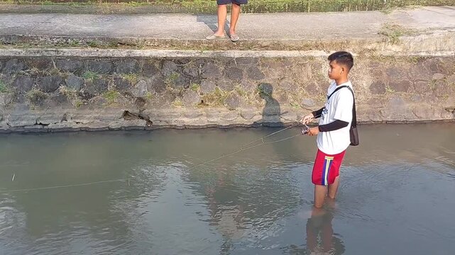 a man who was doing his fishing hobby using casting techniques in a river in the Magelang area, Central Java, Indonesia