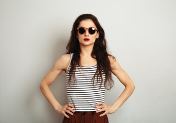 Success sexy  woman posing in fashion sunglasses and stripped t-shirt with red lipstick on white wall background with empty copy space. Fashion lifestyle