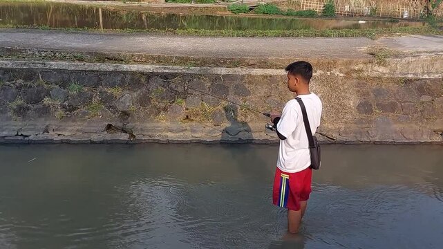 a man who was doing his fishing hobby using casting techniques in a river in the Magelang area, Central Java, Indonesia