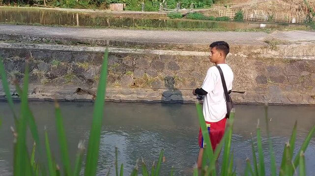 a man who was doing his fishing hobby using casting techniques in a river in the Magelang area, Central Java, Indonesia