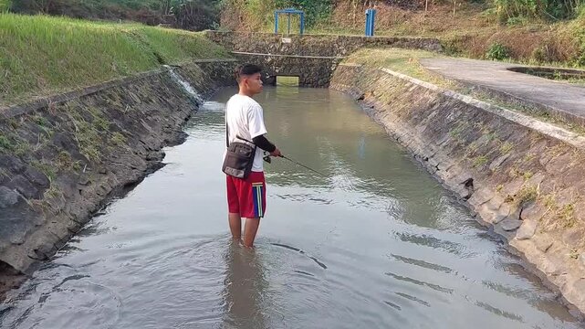 a man who was doing his fishing hobby using casting techniques in a river in the Magelang area, Central Java, Indonesia