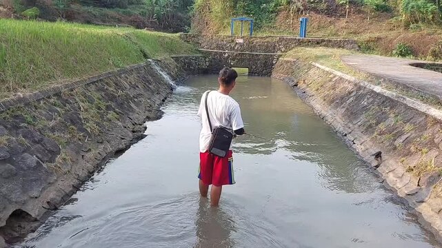 a man who was doing his fishing hobby using casting techniques in a river in the Magelang area, Central Java, Indonesia