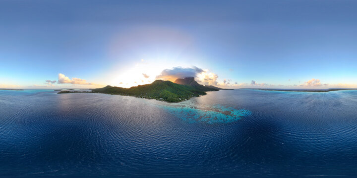 Beautiful panoramic view of vibrant blue ocean water surrounding the tropical island of Bora Bora during sunset