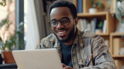 Obraz premium Smiling African-American Man in Business Attire Looking at Laptop