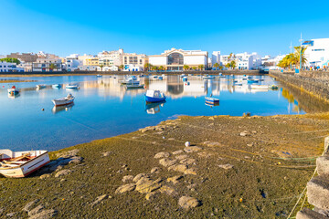Fototapeta premium Colorful small fishing boats float in the Charco de San Gines seawater lagoon at the seaside Spanish town of Arrecife, Spain, on Lanzarote Island, one of the Canary Islands in the Atlantic Ocean. 