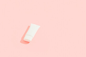 White plastic cosmetic tube on pink background. Cosmetics sale concept