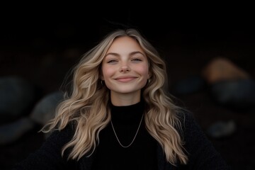 Fototapeta premium Smiling young woman with blonde hair, serene expression in a natural setting