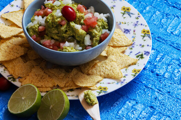 Guacamole inside a blue bowl with chopped tomatoes and onions on top