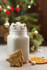 Christmas white drink eggnog with marshmallow on grey background with spruce branches, biscuits and festive bokeh