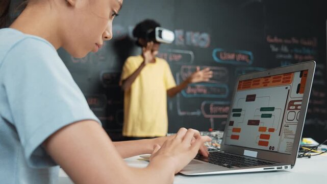 Closeup of school girl hand coding program while african student using VR interact with metaworld. Smart boy wearing virtual reality glasses and playing video games at innovative class. Edification