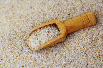Wooden scoop with Psyllium Husk (Isabgol) on the background of Psyllium Husk