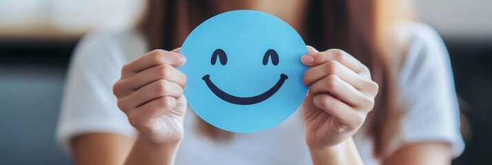 Embracing Positivity: A Woman Crafts a Joyful Smile on Blue Paper for World Mental Health Day, Symbolizing the Importance of Active Thinking and Psychological Well-being.