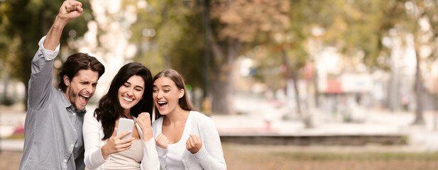 Winners. Three friends reading great message on cell phone, walking together in park, free space