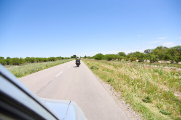 Travel scene: view from the window of a car traveling on an Argentine highway. A motorcycle travels ahead.