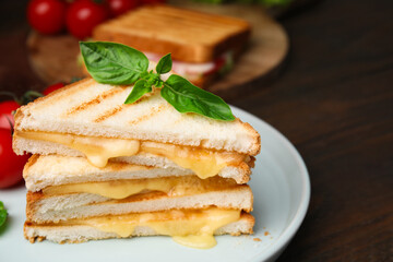 Pieces of toasted bread with melted cheese and basil on wooden table