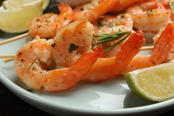 Skewers with delicious grilled shrimps served on plate, closeup
