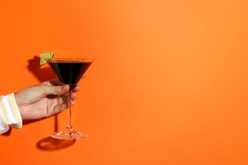 Woman with glass of refreshing cocktail on orange background, closeup. Space for text
