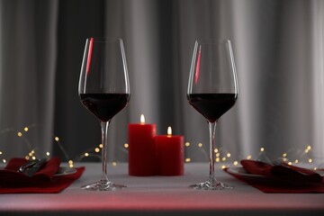 Burning candles and wine in glasses on table against blurred lights
